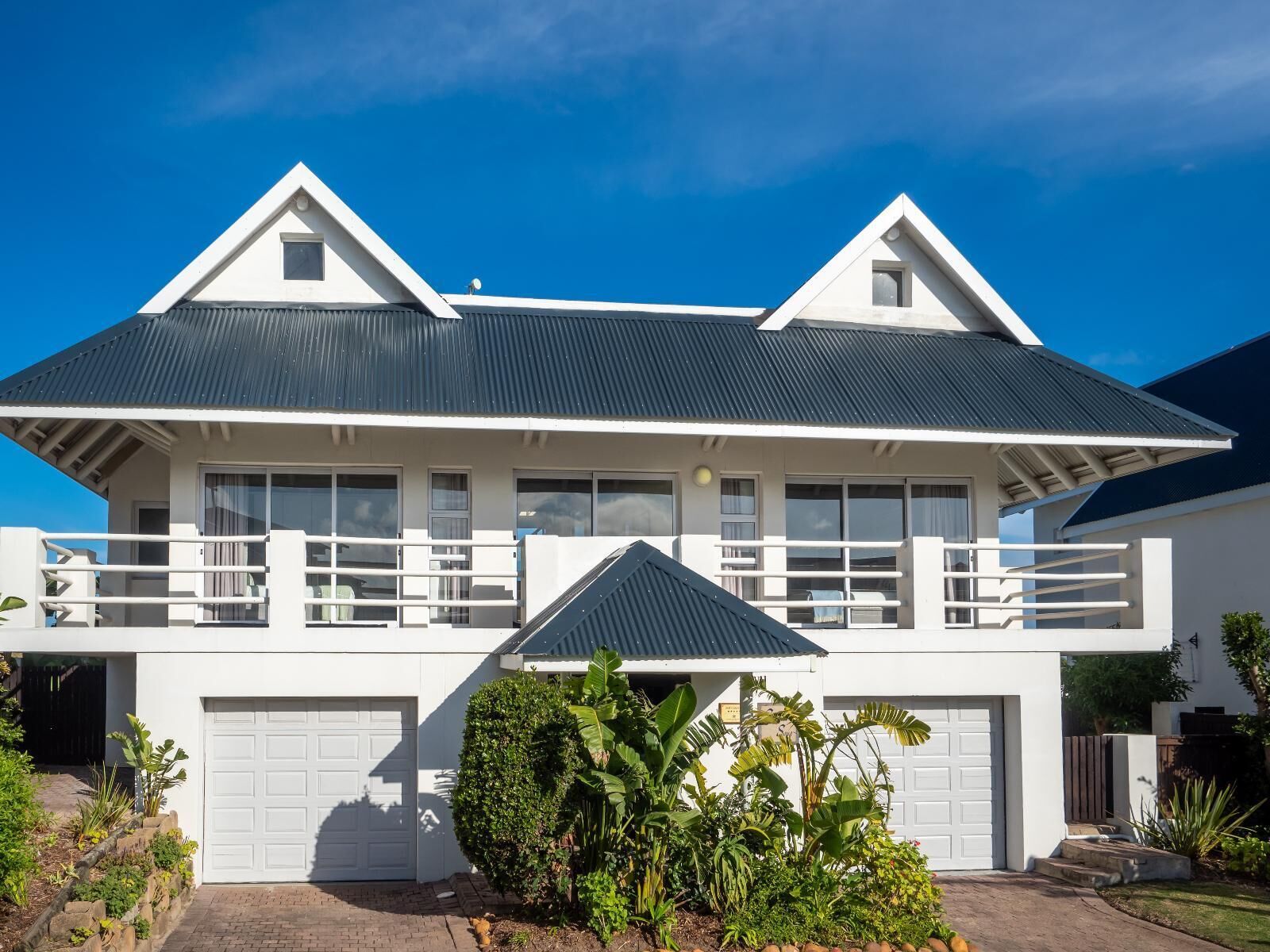 A two-story house with a balcony, a garage, and a well-maintained garden.