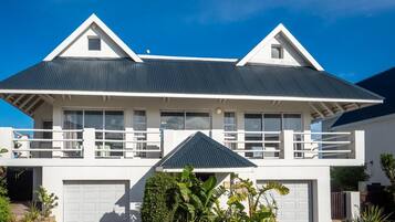 A two-story house with a balcony, a garage, and a well-maintained garden.