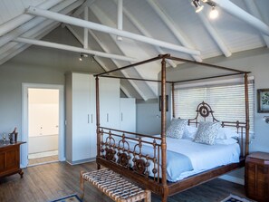 Een hemelbed met houten frame en een bank aan het voeteneinde.