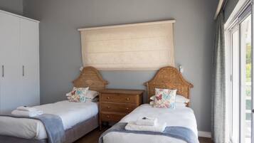 Un dormitorio con dos camas, un aparador de madera y un ventanal grande.