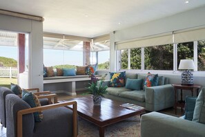 Ein geräumiges Wohnzimmer mit einem großen Fenster, einem Holztisch und einer Sitzecke mit einer Bank und Sofas.