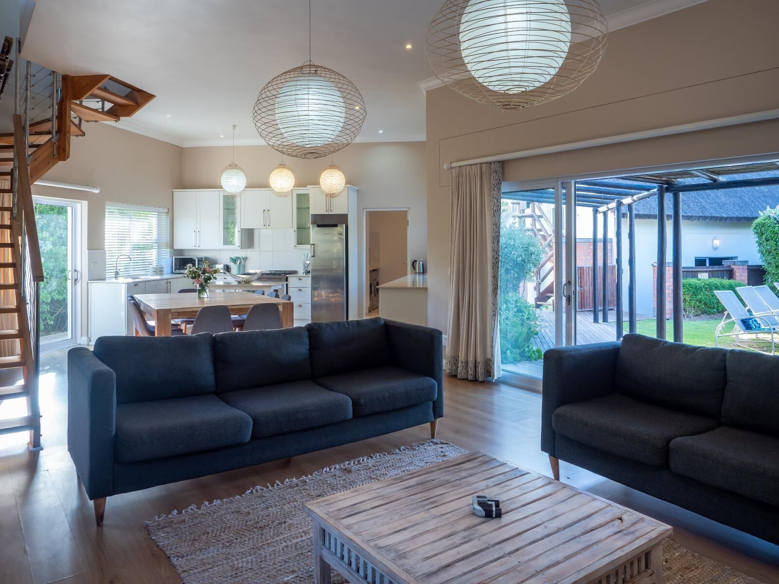 Una sala moderna con un sofá, una mesa de centro y vistas a la cocina y al área exterior.