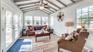 A spacious living room with a high ceiling, large windows, and a cozy seating area.