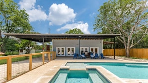 A pool area with a covered patio, seating, and a fenced perimeter.