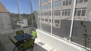 Un balcon doté d’une moustiquaire, d’une table et de deux chaises.