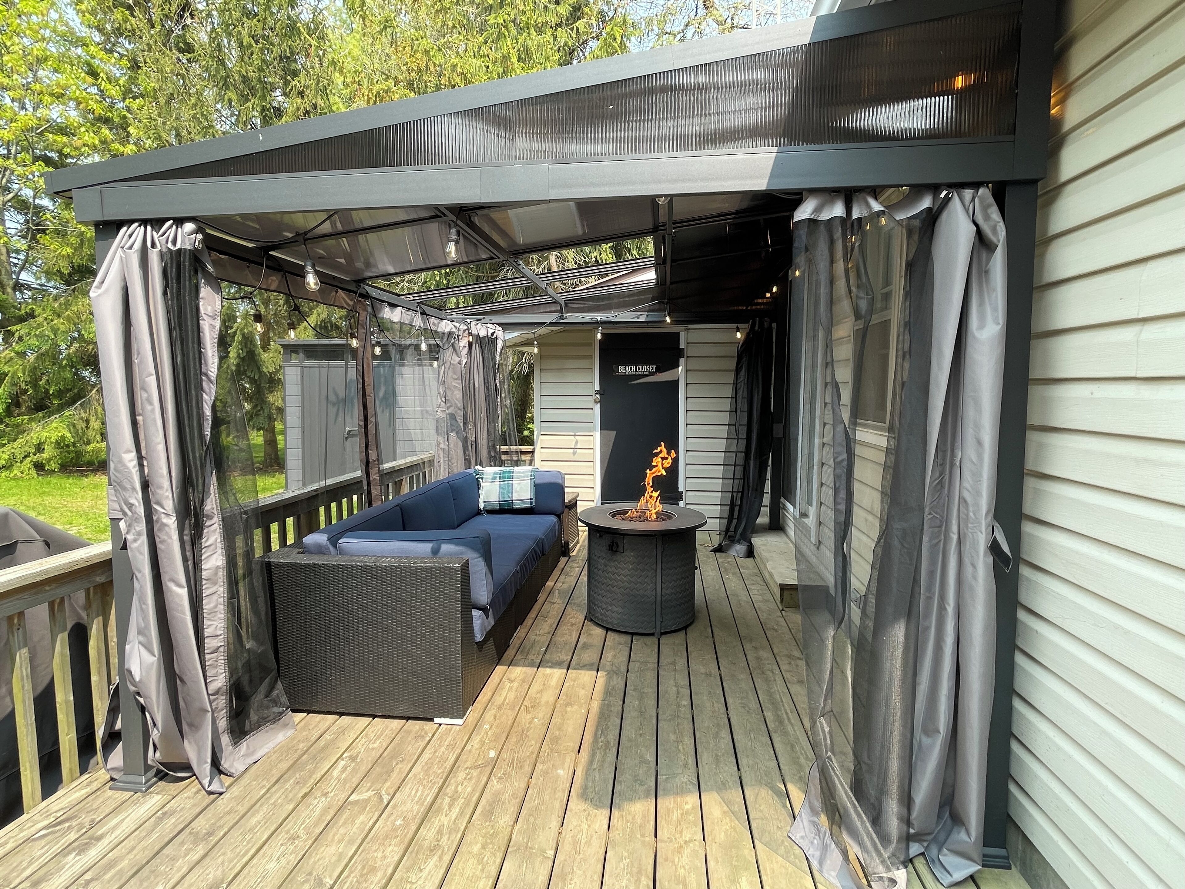 Back deck: Pergola with waterproof roof, curtains, bug screen and fire table.
