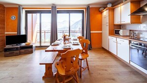 Eine moderne Küche mit Holzausstattung, einer Mikrowelle und einem Essbereich mit Holztisch und Stühlen.
