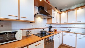 Eine moderne Küche mit weißen Schränken, Holz Arbeitsplatten, einem eingebauten Backofen und einer Kaffeemaschine.