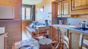 A cozy cabin-style room with a wooden interior, a bed, a dining table with chairs, a coffee maker, and a kettle. - Nice apartment for 4 people with WIFI, pool, TV and pets allowed (Le Corbier)