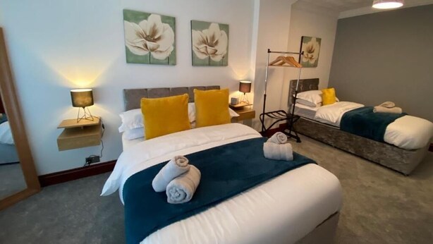 A hotel room with two beds, a mirror, and artwork on the walls. - Cozy Swansea Apartment with 2 Bedrooms (Swansea)