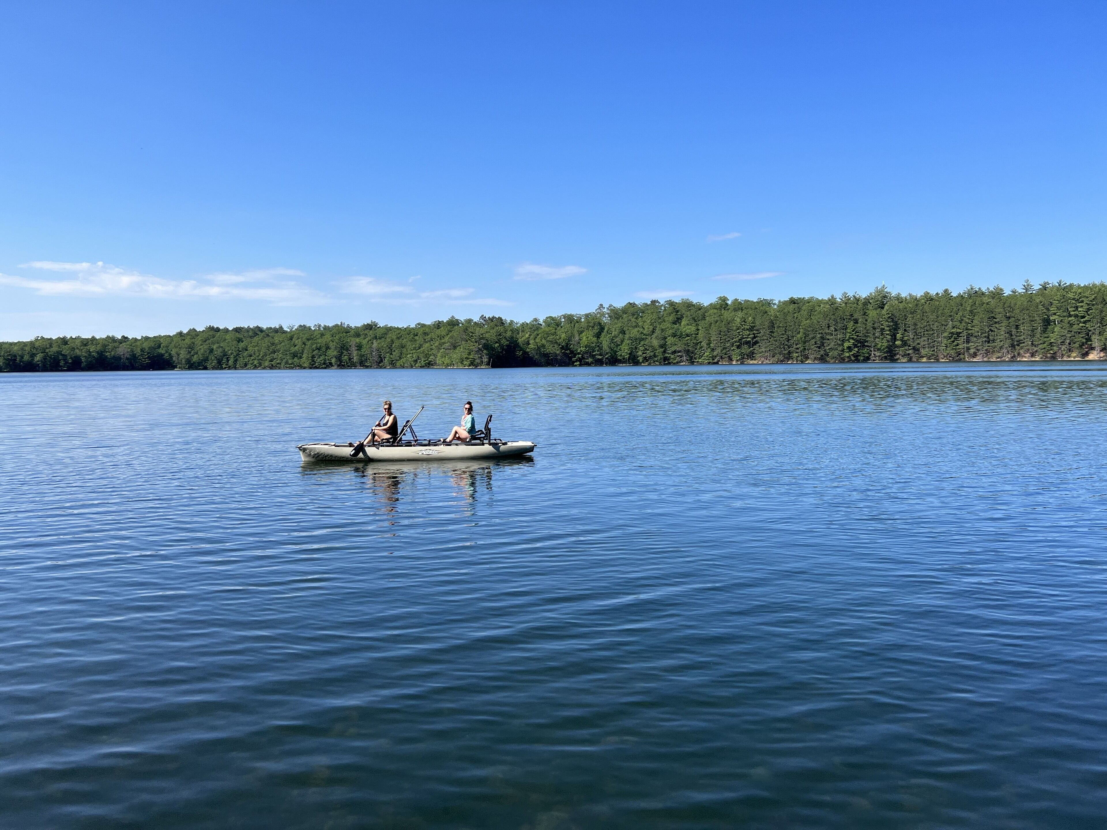 A calm lake with a rowboat carrying two people.