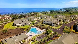 Un quartier résidentiel doté d’une grande piscine entourée de maisons, offrant une vue dégagée sur l’océan et bénéficiant d’un aménagement paysager soigné.