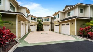 A row of townhouses with attached garages, a central landscaped area, and a clear sky.