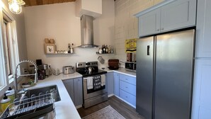 A modern kitchen with stainless steel appliances, white cabinetry, and a wooden ceiling. - River Rock Beach House, Irish Beach private access (Manchester)
