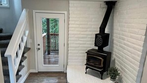 A corner room with a fireplace, a door leading outside, and a staircase. - River Rock Beach House, Irish Beach private access (Manchester)