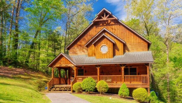 A wooden log cabin with a porch, a front entrance, and a small window. - Right on the river! (Sevierville)
