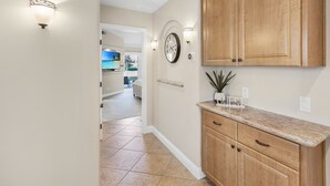 A kitchen with wooden cabinets, a countertop, and a wall-mounted clock. - Two King 👑 Suites,🌴Cozy Palm Desert Home Getaway ❤ 2 Great for Extended Stays! (Palm Desert)