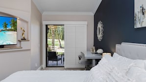 A bedroom with a bed, a desk, a chair, a TV, and a door leading to a balcony. - Two King 👑 Suites,🌴Cozy Palm Desert Home Getaway ❤ 2 Great for Extended Stays! (Palm Desert)