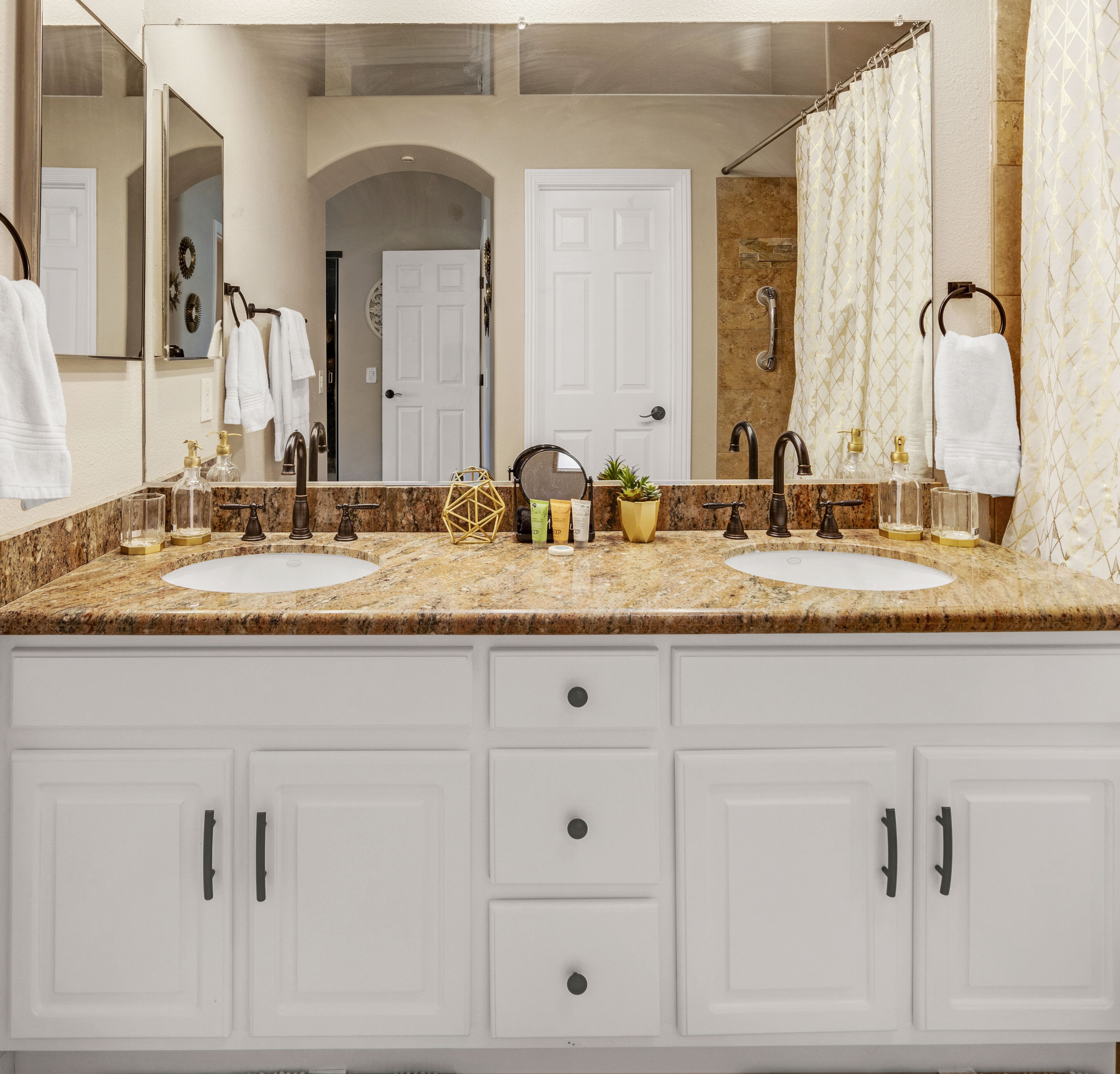 A bathroom with two sinks, a large mirror, and a shower area.