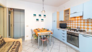 Una cocina funcional con mesa, sillas, estufa y televisor.