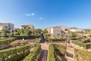 A residential area with stone buildings, a paved pathway, and well-maintained greenery.