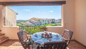 Varanda com mesa posta para refeição, oferecendo vista panorâmica de edifícios e vegetação.