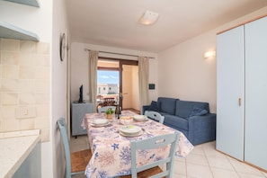 A dining area with a table set for two, a blue sofa, and a wardrobe.