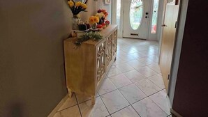 A hallway with a wooden console table, a mirror, and a chandelier. - The Majestic Retreat Estate (West Lawn)