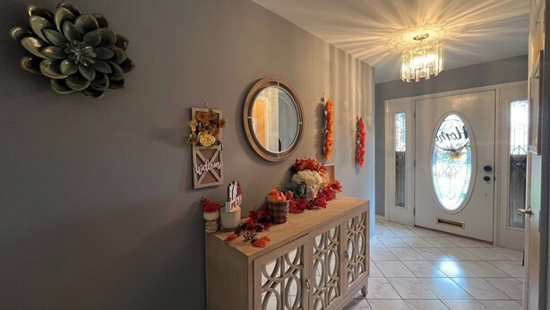 A hallway with a decorative console table, a mirror, and a door with a frosted glass window. - The Majestic Retreat Estate (West Lawn)