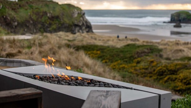 Un foyer extérieur offrant une vue sur l’océan et la plage en arrière-plan.
