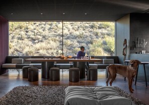Un interior moderno con un ventanal grande, una zona de comedor y un perro.