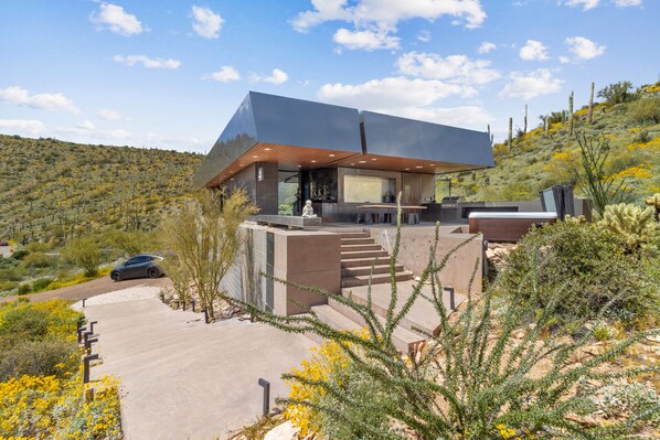 Una casa moderna con techo plano, ventanas amplias y un patio.