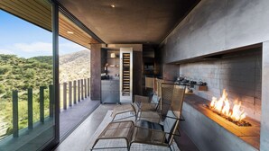Un espace extérieur moderne, aménagé pour se détendre, avec un foyer, une cuisine et une vue sur le paysage désertique.