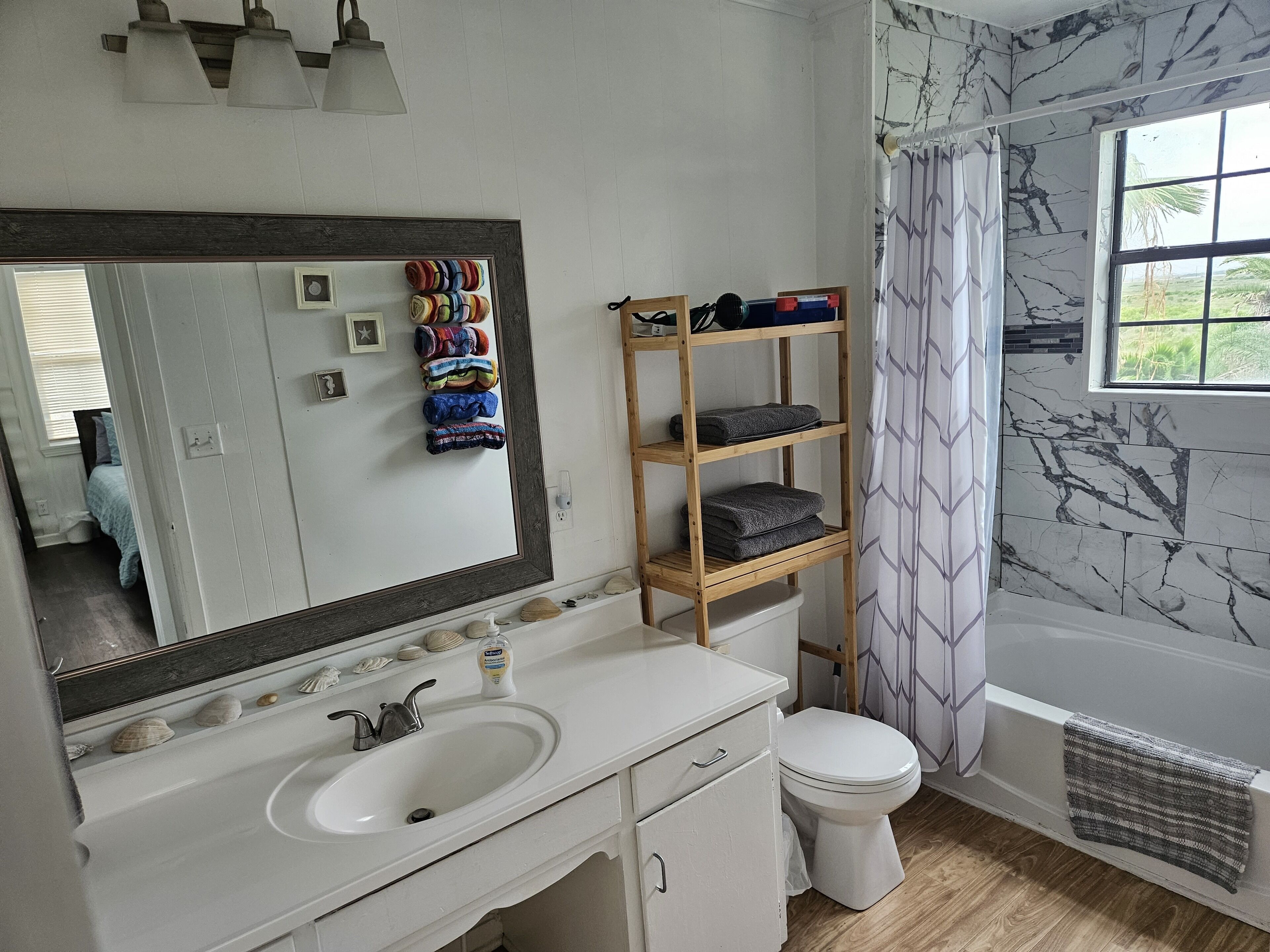 A bathroom with a white sink, mirror, and wooden shelves with towels.