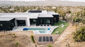 A modern house with a swimming pool, outdoor seating, and a view of the surrounding landscape. - Joshua Tree Hot Tub, Pool, Gym & Fireplace (Yucca Valley)