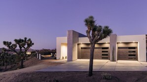 A modern house with a driveway, garage, and desert landscaping. - Joshua Tree Hot Tub, Pool, Gym & Fireplace (Yucca Valley)