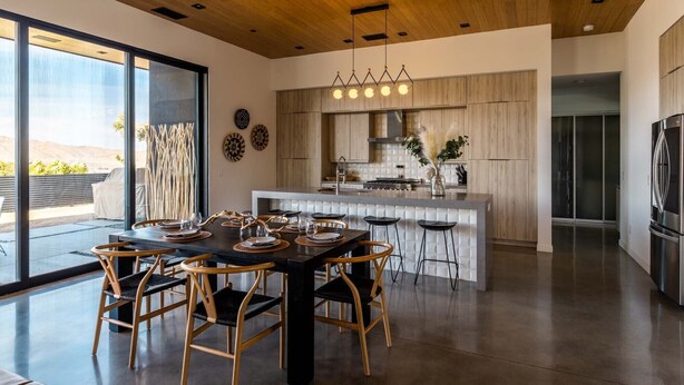 A modern kitchen with a central island, wooden cabinets, and a stainless steel refrigerator. - Joshua Tree Hot Tub, Pool, Gym & Fireplace (Yucca Valley)