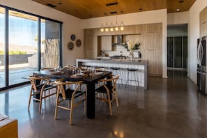 A modern kitchen with a central island, wooden cabinets, and a stainless steel refrigerator.