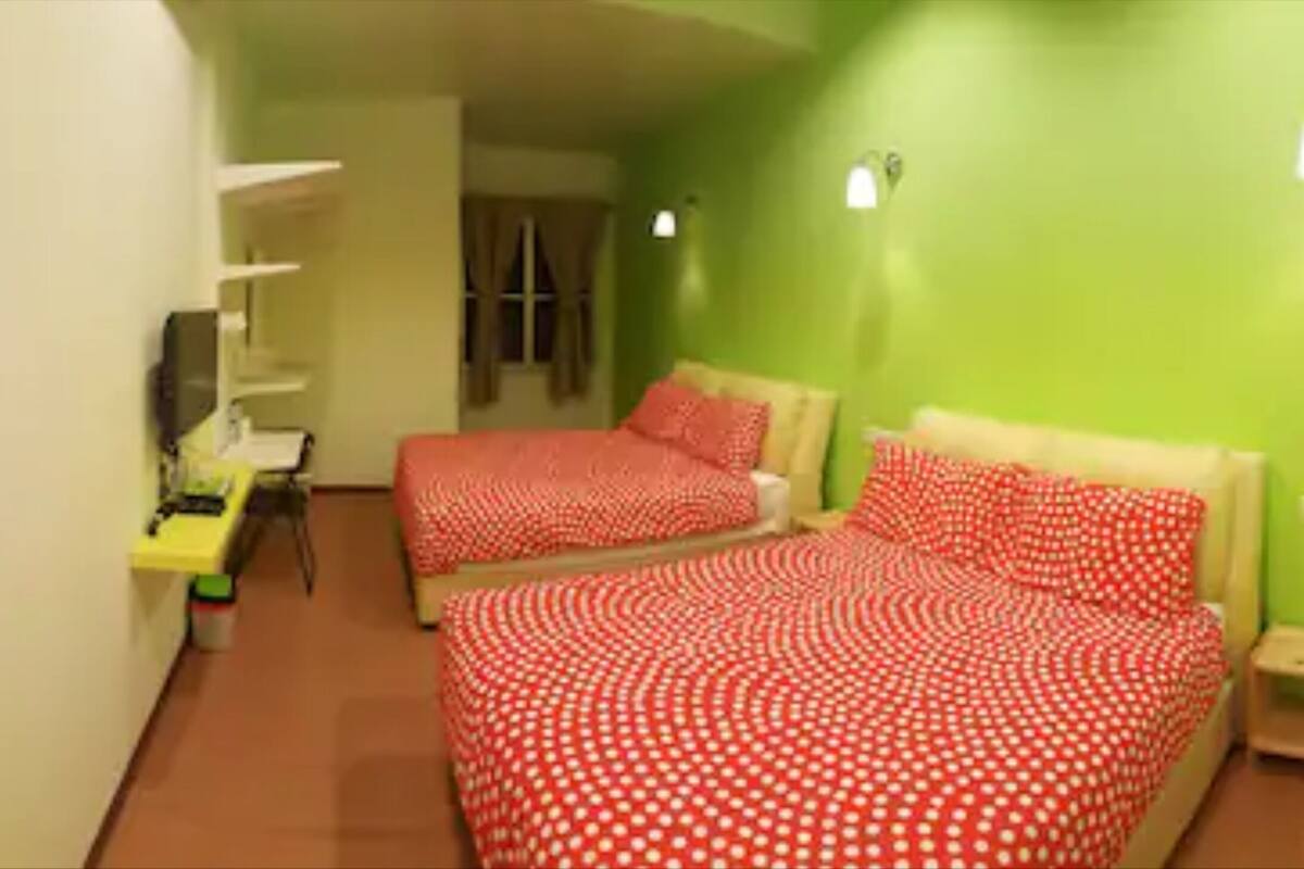 Ein Zimmer mit zwei Betten, einem Schreibtisch und einem Stuhl.