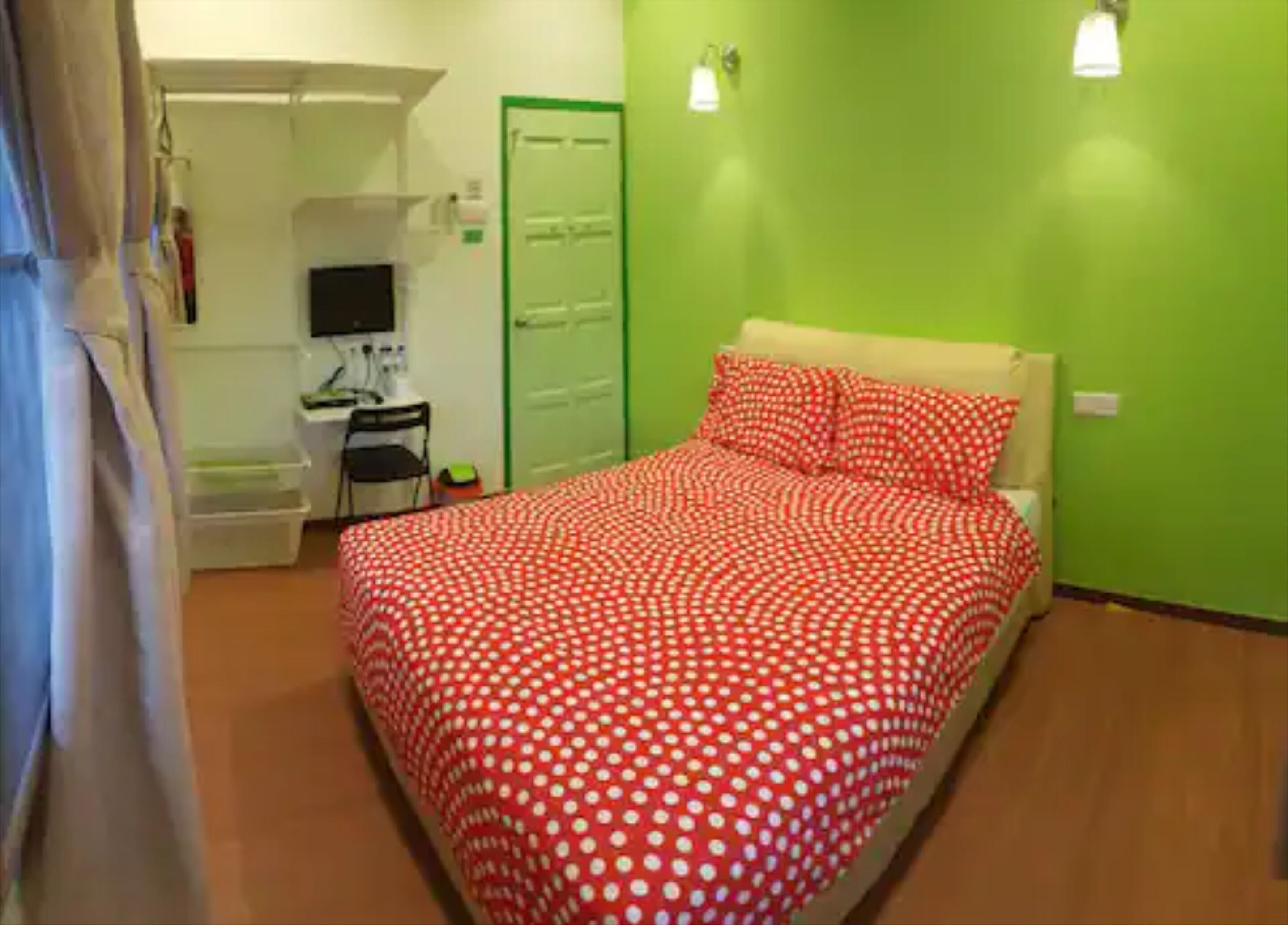 Un dormitorio con una cama, un escritorio, una silla y una pared verde.