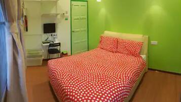 Un dormitorio con una cama, un escritorio, una silla y una pared verde.
