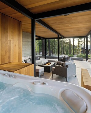 A modern outdoor hot tub area with a wooden deck, grey sofas, and a fire pit. - Tahoe Slopes / Ski-In/Out, Hot Tub, BBQ & Fire Pit (Truckee)