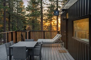 Terraza con mesa y sillas, zona de estar con vistas a un bosque y un cartel que dice "Wander".