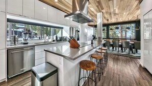 Une cuisine moderne dotée d’un îlot central, de tabourets de bar et offrant une vue sur l’extérieur.