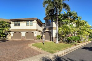 A two-story house with a brick driveway, a garage, and a well-maintained lawn with palm trees. - Waiola Realty - Renovated Tranquil Ho'olei Ocean View Villa 39-2 Wailea Maui (Kihei)