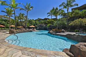 A pool area with clear blue water, surrounded by palm trees and rocks. - Waiola Realty - Renovated Tranquil Ho'olei Ocean View Villa 39-2 Wailea Maui (Kihei)