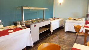 A buffet setup with multiple serving stations, a beverage dispenser, and a seating area with tables and chairs.