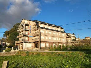 A multi-story hotel with a central staircase, balconies, and a sign indicating it is a hotel. - Hotel Acquamaris 3000 (Sanxenxo)