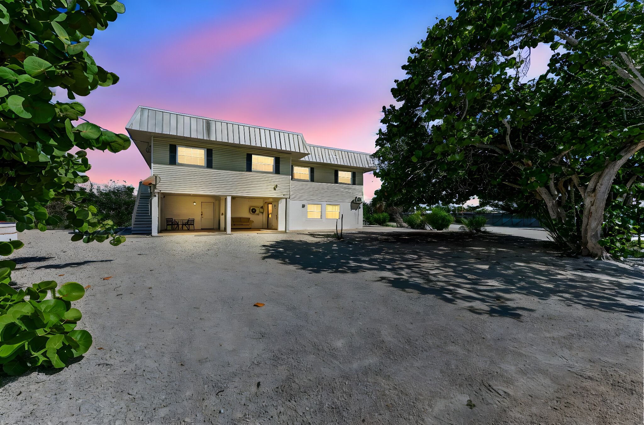 Une maison moderne à deux étages avec un garage, entourée de verdure.