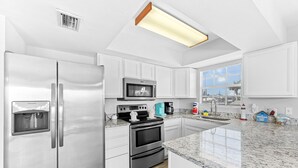 A modern kitchen with stainless steel appliances, a built-in oven, and a granite countertop. - Huge Shared Pool, Walk to Beach, Times Square Restaurants! (Fort Myers Beach)